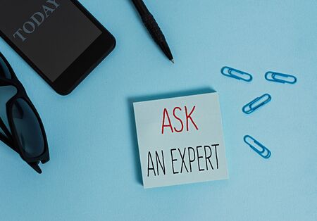 Text sign showing Ask An Expert. Business photo text consult someone who has skill about something or knowledgeable Eyeglasses colored sticky note smartphone cell clips pen pastel backgroundの写真素材