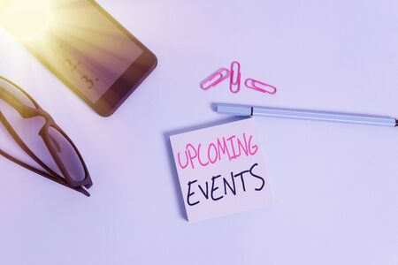 Word writing text Upcoming Events. Business photo showcasing the approaching planned public or social occasions Eyeglasses colored sticky note smartphone cell clips pen pastel backgroundの写真素材