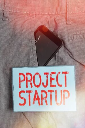 Handwriting text writing Project Startup. Conceptual photo the initial opportunity of a young company to set their plan Smartphone device inside formal work trousers front pocket near note paperの写真素材