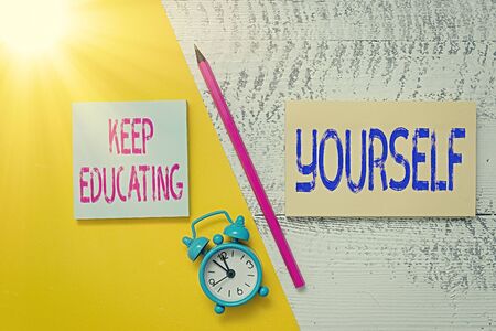 Handwriting text writing Keep Educating Yourself. Conceptual photo dont stop studying Improve yourself using Courses Notepads marker pen colored paper sheet alarm clock wooden backgroundの写真素材