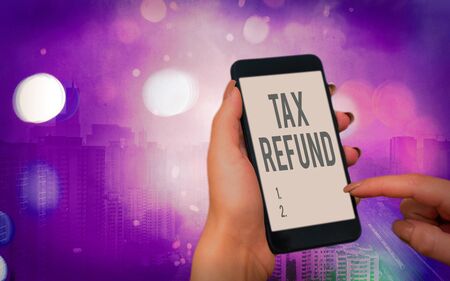 Word writing text Tax Refund. Business photo showcasing excess payment of paid taxes returned to business owners Modern gadgets with white display screen under colorful bokeh backgroundの写真素材