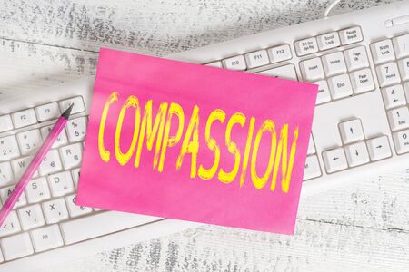 Handwriting text writing Compassion. Conceptual photo empathy and concern for the pain or misfortune of others White keyboard office supplies empty rectangle shaped paper reminder woodの写真素材