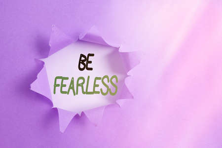 Writing note showing Be Fearless. Business concept for act of striving to lead an extraordinary life and make a difference Rolled ripped torn cardboard above a wooden classic tableの写真素材