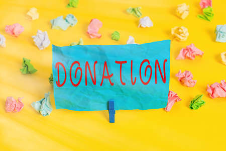 Conceptual hand writing showing Donation. Concept meaning something that is given to a charity, especially a sum of money Colored crumpled paper empty reminder white floor clothespinの写真素材