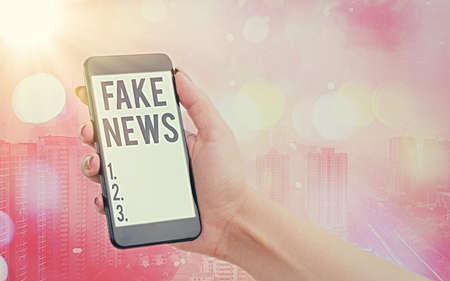 Handwriting text Fake News. Conceptual photo false information publish under the guise of being authentic news Modern gadgets with white display screen under colorful bokeh backgroundの写真素材