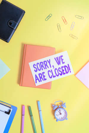 Text sign showing Sorry, We Are Closed. Business photo text apologize for shutting off business for specific time Flat lay above table with copy space paper clips clock and pencilsの写真素材