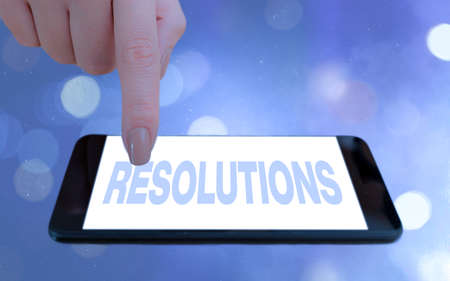 Conceptual hand writing showing Resolutions. Concept meaning the act of analyzing a complex notion into simpler ones Modern gadgets white screen under colorful bokeh backgroundの写真素材