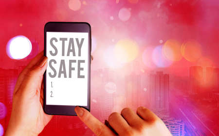 Word writing text Stay Safe. Business photo showcasing secure from threat of danger, harm or place to keep articles Modern gadgets with white display screen under colorful bokeh backgroundの写真素材