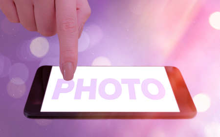 Conceptual hand writing showing photo. Concept meaning defined as produced by light, image taken with the help of light. Modern gadgets white screen under colorful bokeh backgroundの写真素材