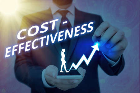 Writing note showing Cost Effectiveness. Business concept for degree to which something is effective in relation to its cost. Arrow symbol going upward showing significant achievementの写真素材