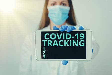 Writing note showing Covid 19 Tracking. Business concept for Distinguishing process of the possible infected individuals Laboratory technician featuring empty paper accessories smartphoneの写真素材