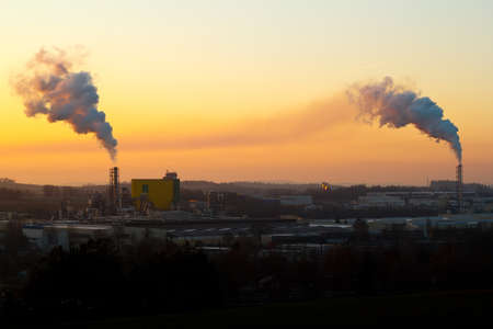 Sunrise silhouette of city landscape with smoking factoryの写真素材
