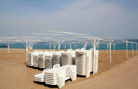 Empty beach with white sun lounger before tourist seasonの写真素材