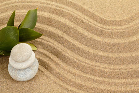 background with balance zen stones in sand and green leavesの写真素材