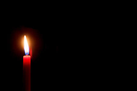 burning red candle with black background and space for textの写真素材