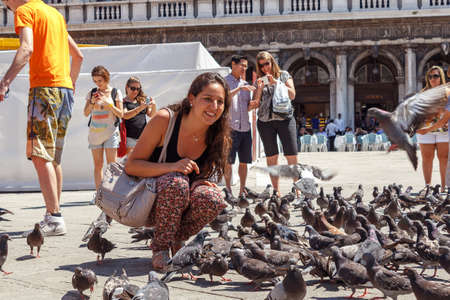 ITALY, VENICE - JULY 2012: Woman with pigeons on most famous square July 16, 2012 in Venice. More than 20 million tourists come to Venice annually.のeditorial素材