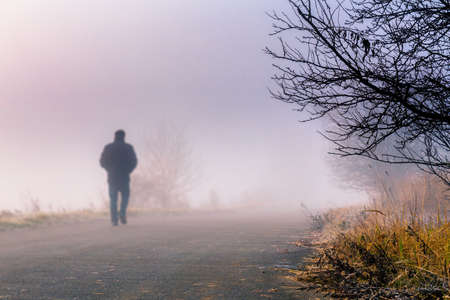 A person walk into the misty foggy road in a dramatic sunrise scene with abstract colors