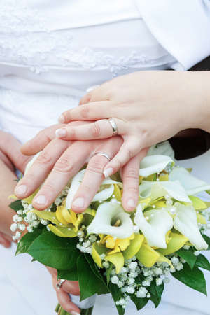 Bride and groom's hands with wedding rings with bouquetの写真素材