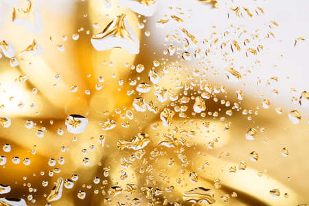 golden abstract background with water drops on glass with gold ribbon in background の写真素材