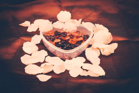 Brightly coloured red gums hearts as valentine present with rose petals on red retro colorの写真素材
