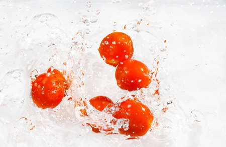 fresh small red cherry tomatoes with water splashの写真素材