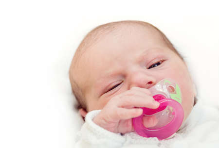 Face of adorable baby with pacifier in mouth looking at camera, the first hours of the new lifeの写真素材