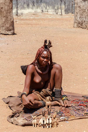 NAMIBIA, KAMANJAB, OCTOBER 10: Himba girl with souvenirs for sale in the Himba village in northern...