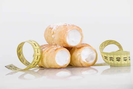 concept of slimming, cakes with measuring tape on white backgroundの写真素材