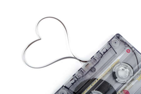 Audio cassette tape isolated on white backgound. Film shaping heart, Valentine postcard. Label text love songs.の写真素材