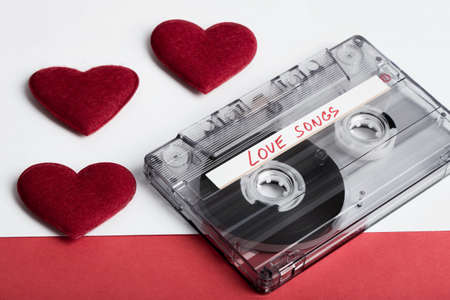 Audio cassette tape on red backgound with fabric heart, Valentine postcard. Love concept with evelopeの写真素材