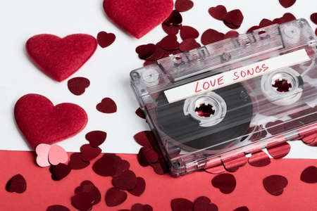 Audio cassette tape on red backgound with fabric heart, Valentine postcard. Love concept with evelope and confettiの写真素材