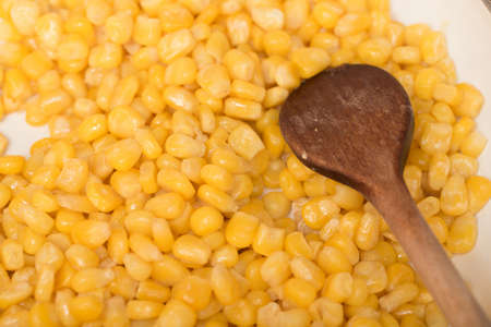 macro of cooking sweet conn with wooden spoon