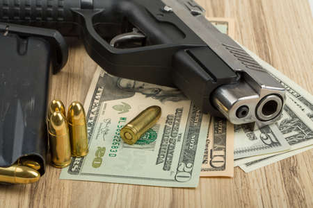 detail of gun with bullet on US dollar banknotes, crime or corruption conceptの写真素材