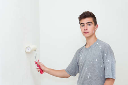 happy young teenager painting wall to white at homeの写真素材