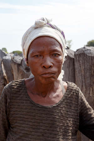 NAMIBIA, KAVANGO, OCTOBER 15: An unidentified old wrinkled woman behind gate of his village in Namibia, Kavango region, with the highest poverty level in Namibia. October 15, 2014, Namibiaのeditorial素材