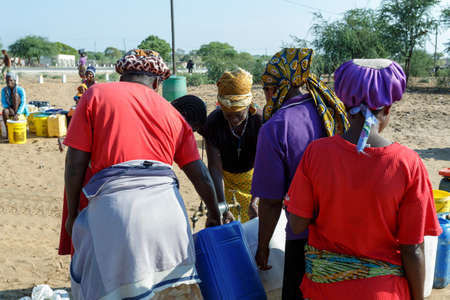 NAMIBIA, KAVANGO, OCTOBER 15: Unidentified Namibian woman with child near public tank with drinking water.Kavango region. October 15, 2014, Namibiaのeditorial素材