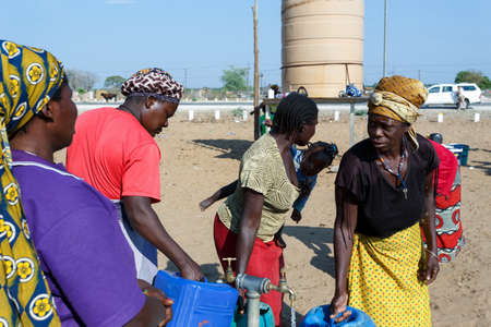 NAMIBIA, KAVANGO, OCTOBER 15: Unidentified Namibian woman with child near public tank with drinking water.Kavango region. October 15, 2014, Namibiaのeditorial素材
