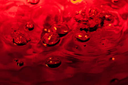 red abstract background with water drops on glass for background or backdropの写真素材