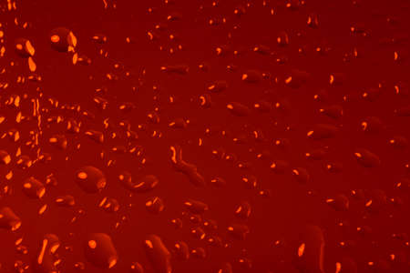 red abstract background with water drops on glass for background or backdropの写真素材