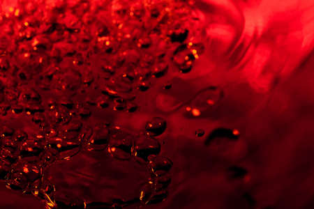 red abstract background with water drops on glass for background or backdropの写真素材
