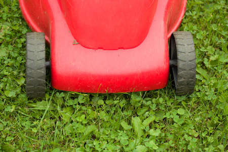 red lawnmower on green grass in cloudy day