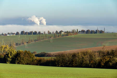 non ecologic smoking chimneys in from factory hidden in morning mist over rural landscapeの写真素材