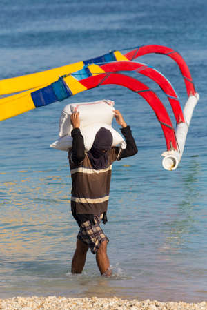 BALI, NUSA PENIDA ISLAND, INDONESIA - JULY 29.2015: Men transports cargo from ship in the hands. There is no other possibility to transport. Nusa Penida July 29. 2015 Indonesiaのeditorial素材
