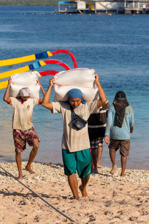 BALI, NUSA PENIDA ISLAND, INDONESIA - JULY 29.2015: Men transports cargo from ship in the hands....