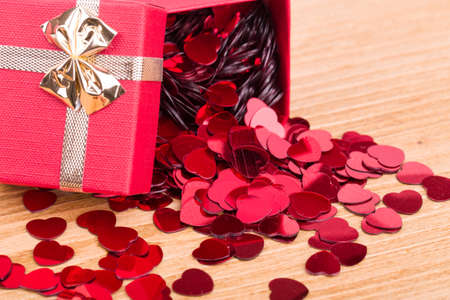 small red hearts confetti and present box on wooden backgroundの写真素材