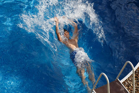 Boy jumping in the home garden swimming pool with clear waterの写真素材
