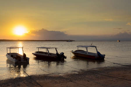 sunset on Bali sea, Nusa Penida Island, Toyapakeh, Indonesia - boat with silhouette of Lembogan at evening with dramatic skyの写真素材