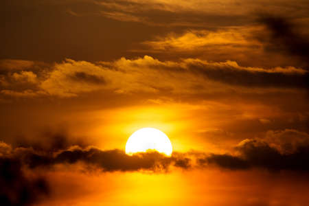 sunset with sun clouds over clouds. Spring scene. Dusk sky with sun hiding in clouds. Spring sunsetの写真素材