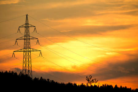 sunset with electricity tower in countryside. Spring scene. Dusk sky with sun. Spring sunset