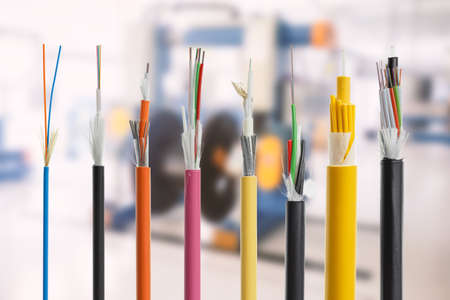 Collection of fiber optical cables on blurry production room background. Loose tubes with optical...